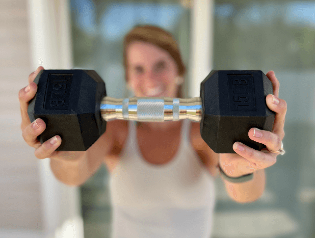 Hannah holding a dumbbell toward the camera